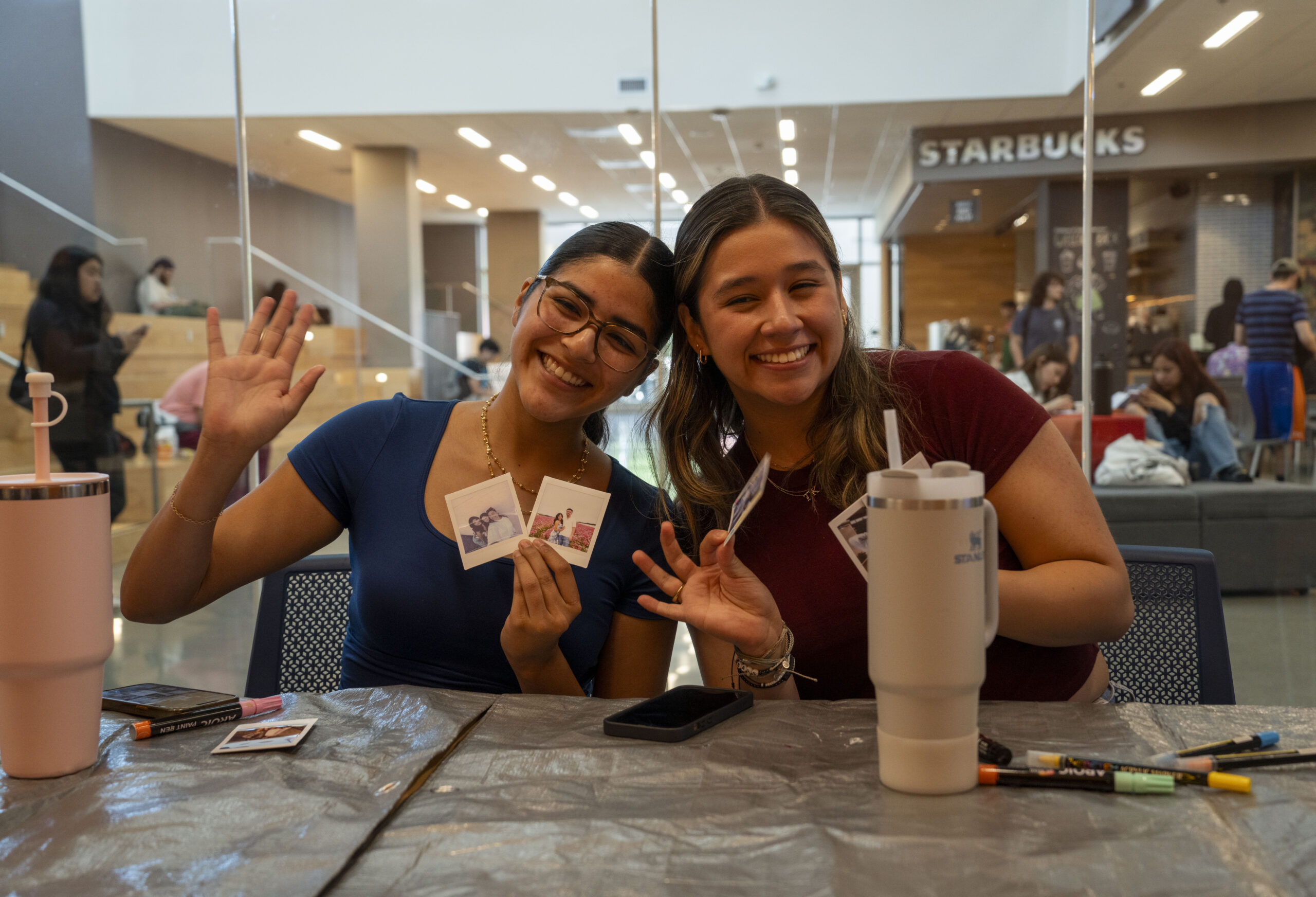 two girl CSUF students pose for a picture while holding their crafts.