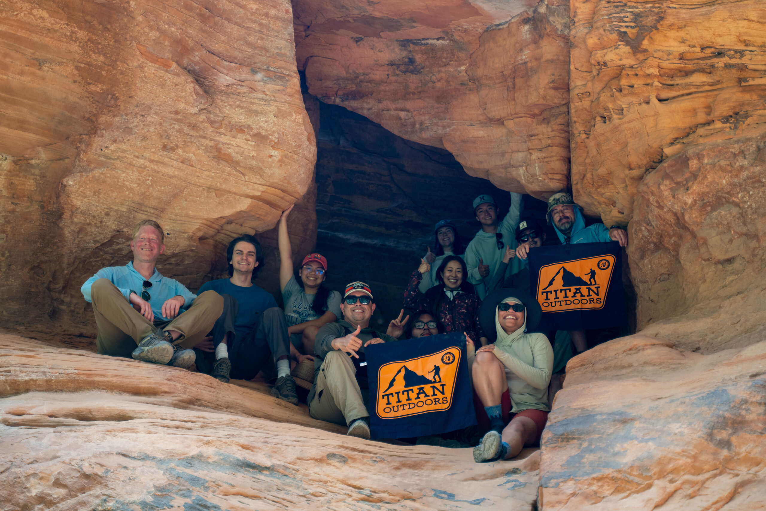 Titan Outdoors take a group photo in a Zion cave while posing with Titan Outdoor merch.