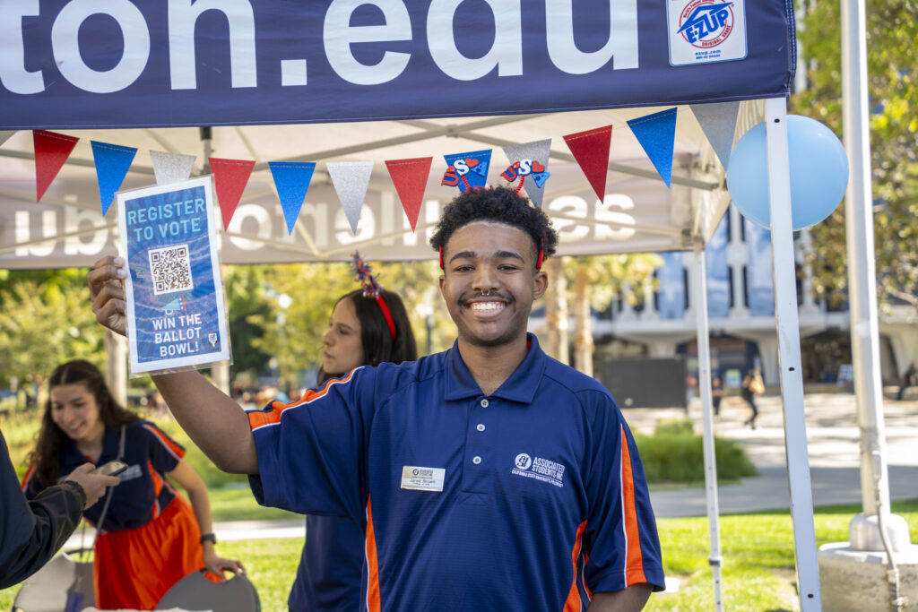 A man holds up a sign encouraging students to register to vote.