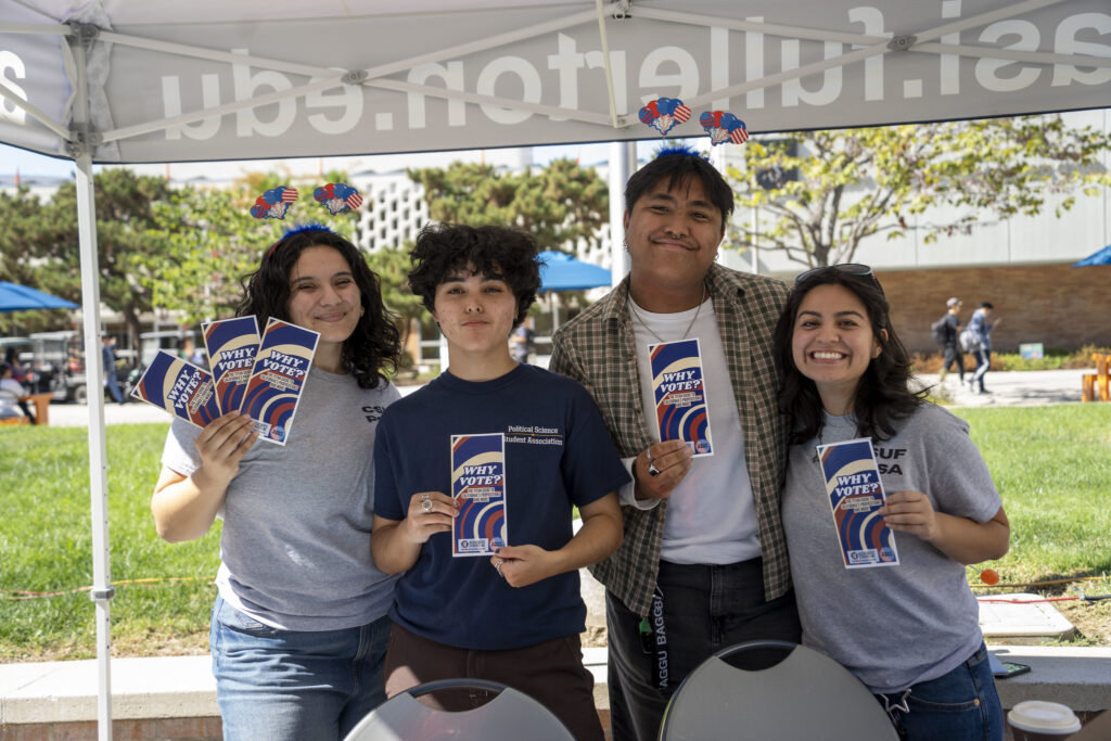 Four students hold up pamphlets that ask, "Why Vote?"