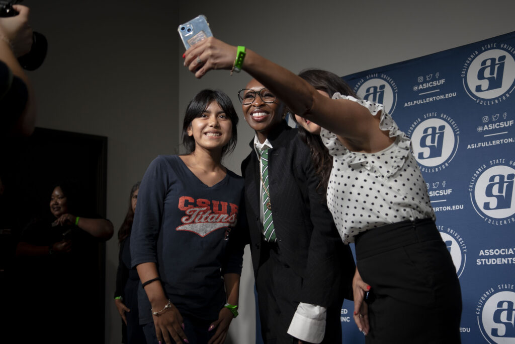 Erivo poses for a picture with a woman and a student while smiling