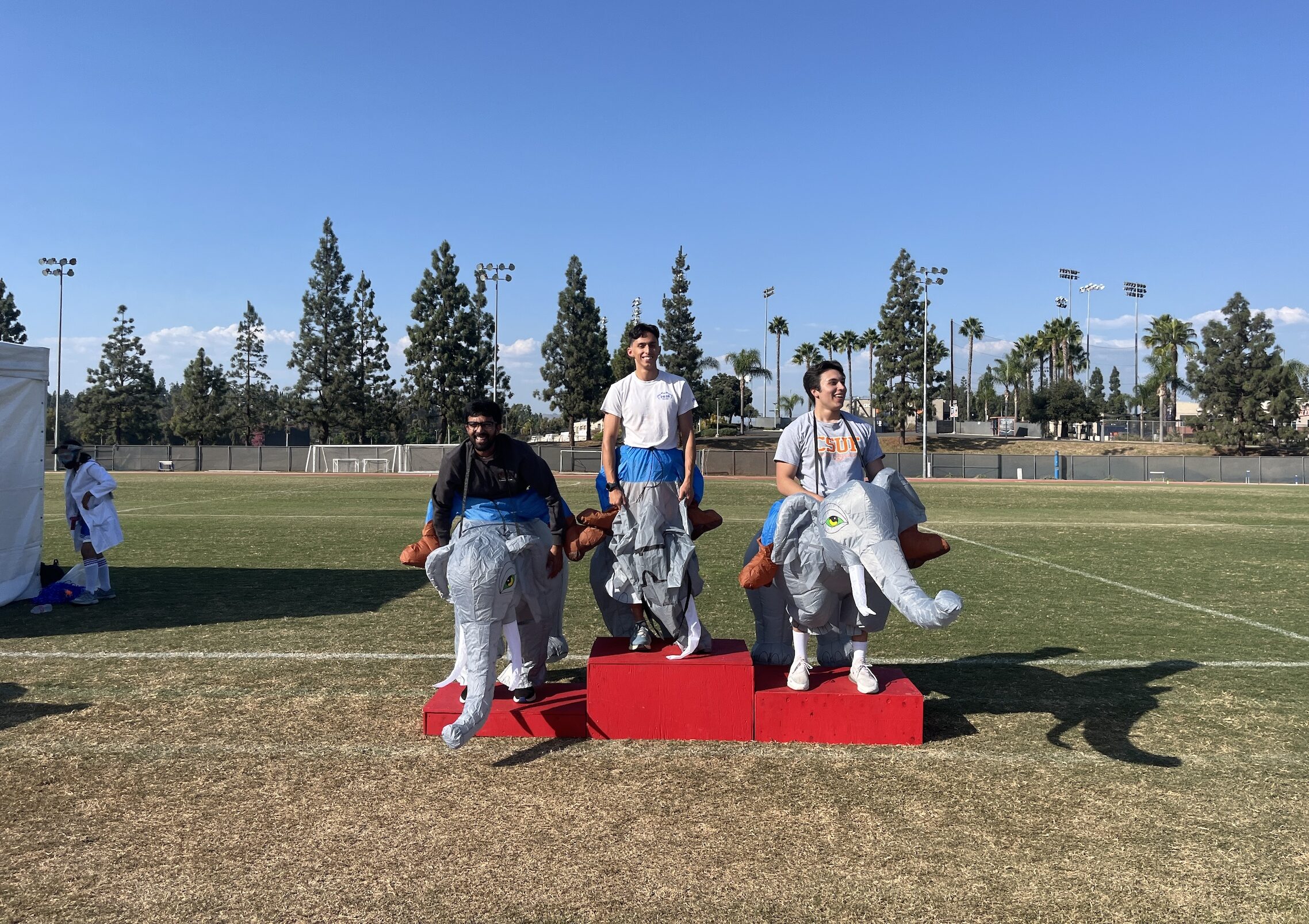 three young men posing on a pedestal in elephant inflatable outfits