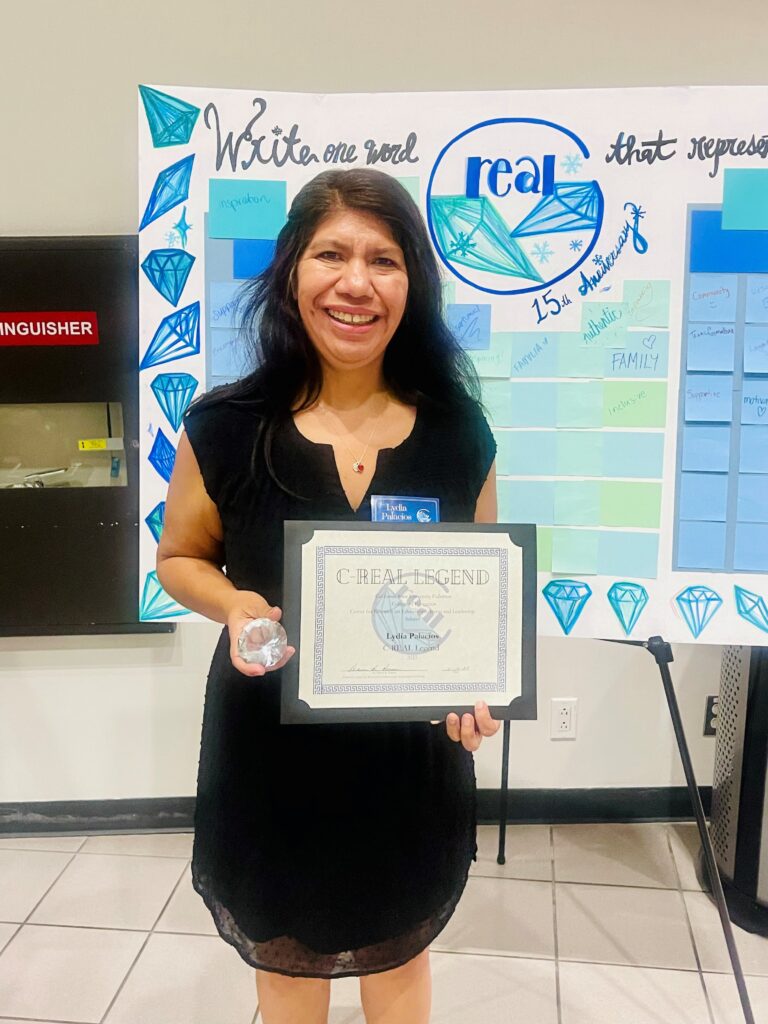 Lydia Palacios posing with her C-REAL award certificate and a trolphy diamond. 