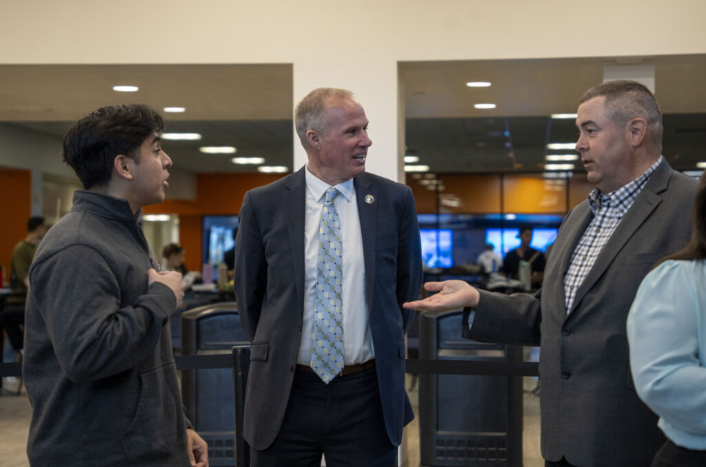 Three men engage in conversation.