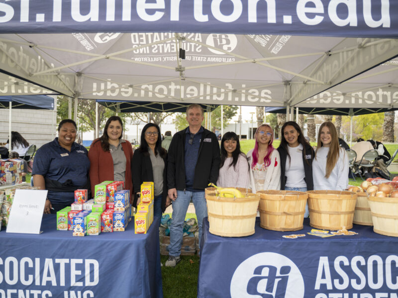 Food Pantry volunteers pose for a photo in back of an ASI table with food.