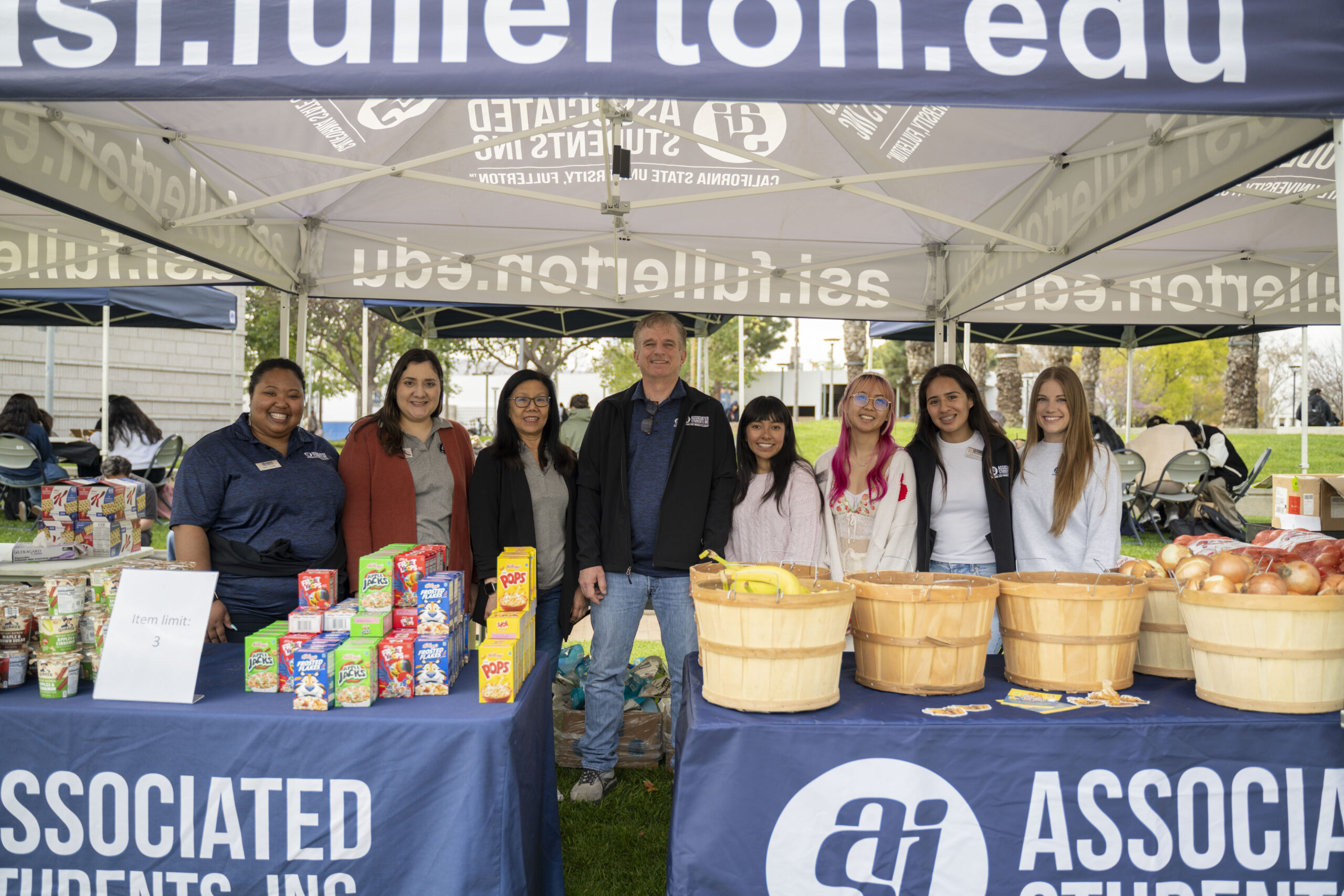 Food Pantry volunteers pose for a photo in back of an ASI table with food.