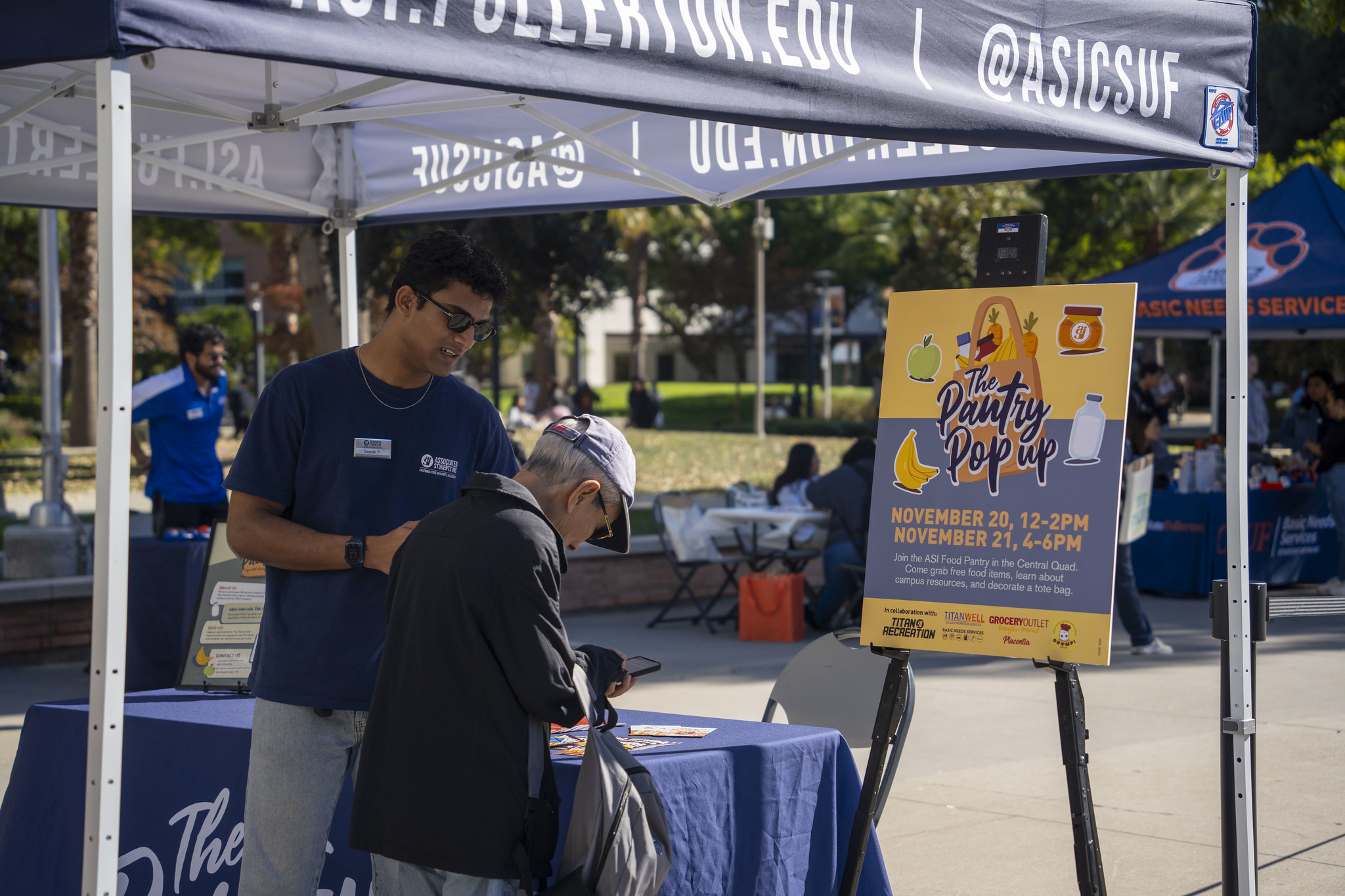 An ASI worker assists someone on their phone in front of a sign that says, "The Pantry Pop-Up".