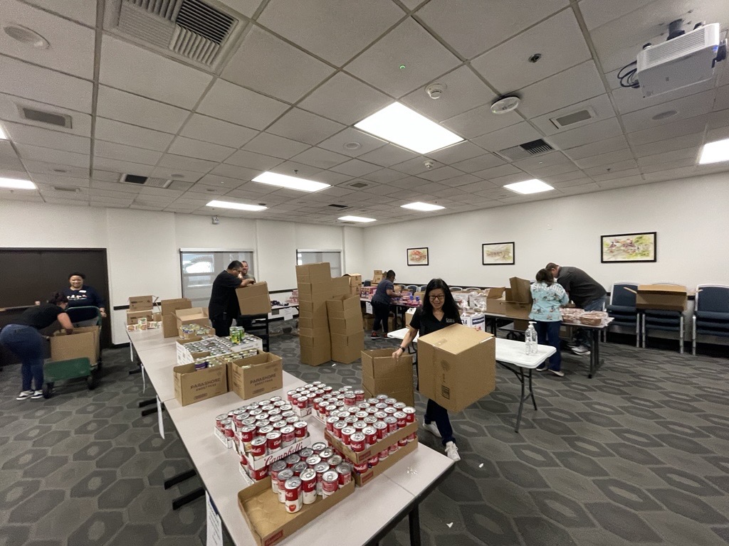 People in room with tables and canned goods 