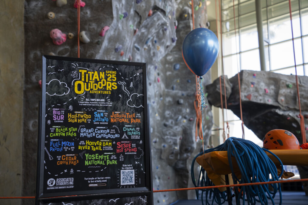  a shot of the climbing wall in the SRC with the Titan Outdoor Spring schedule and a blue balloon