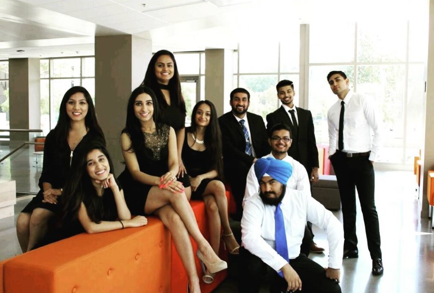 Indian students dressed in suits and dresses and posing for a picture 