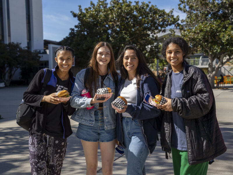 a group og young college girls posing for a picture holding hamburgers