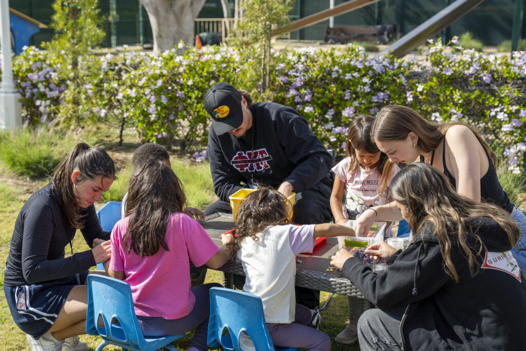 group of kids sitting outdoors around a table