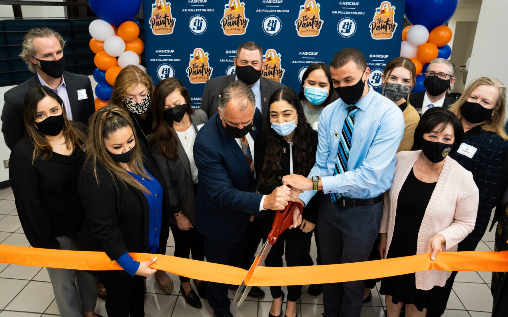 a group of people ribbon cutting with big scissors