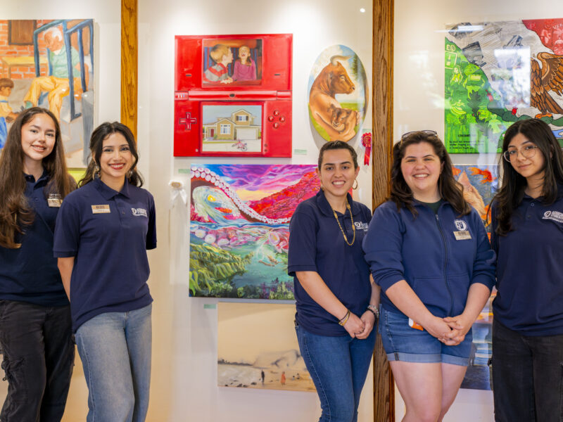 a group of young women standing in front of an art exhibit