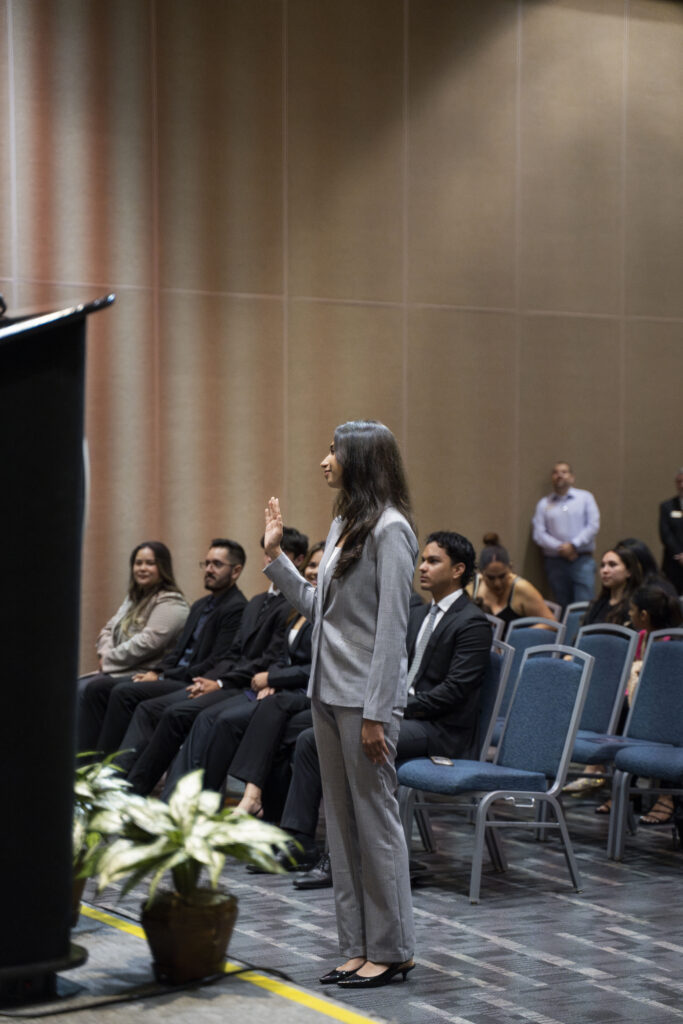 a young woman in a grey suit standing before a podium