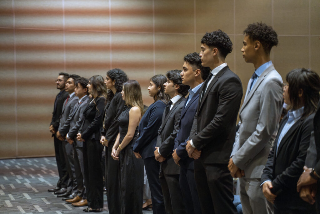 a group of students dressed in suits standing beside eachother in a line