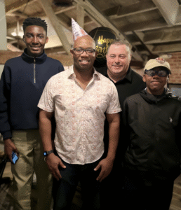 two men standing alongside teenage boys