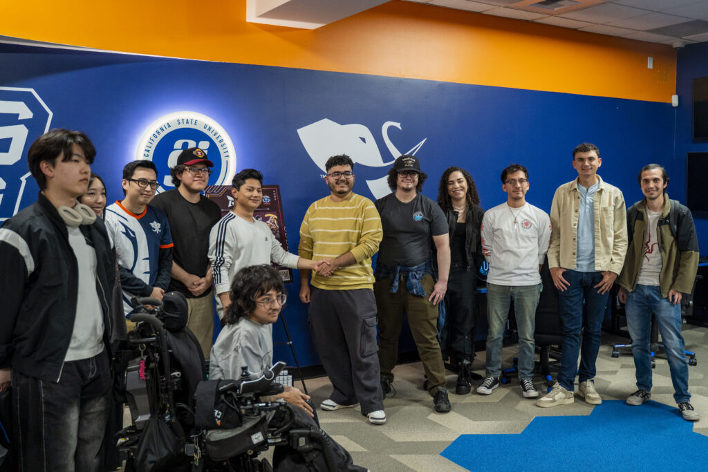 Group of students standing and smiling in front of ASI sign while smiling and shaking hands. 