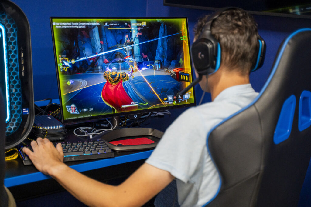 College student sitting in gaming chair playing Marvel Rivals.