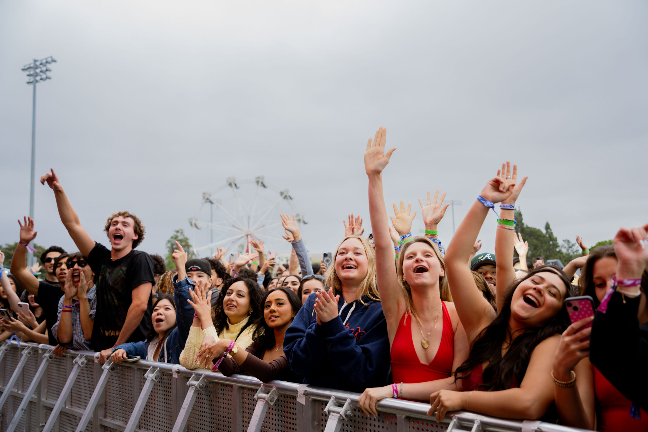 a group of students cheering behind a barricade at a concert