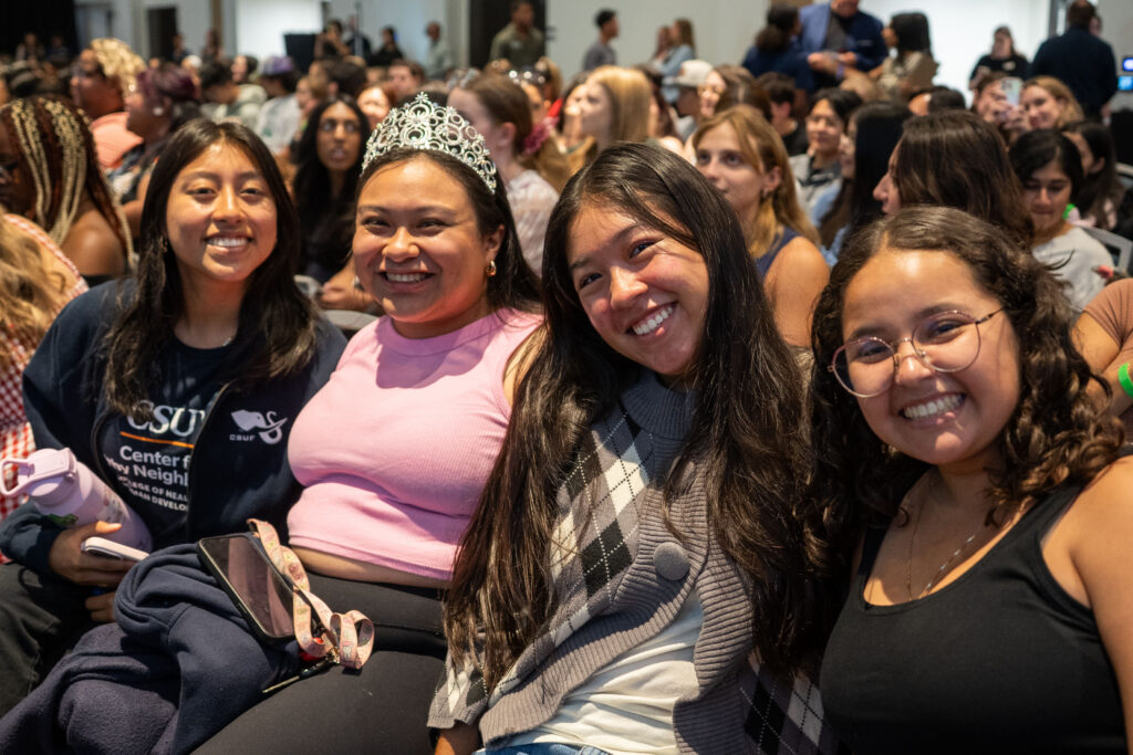 Students smile at camera in the audience. 