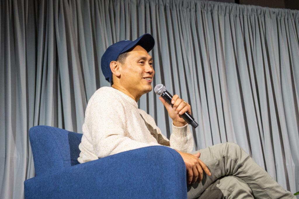 Jon M. Chu holds microphone on stage.