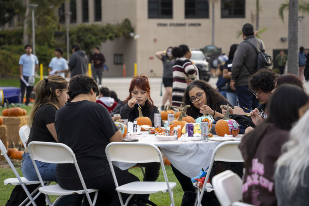 a group of students paint pumpkins on a table together