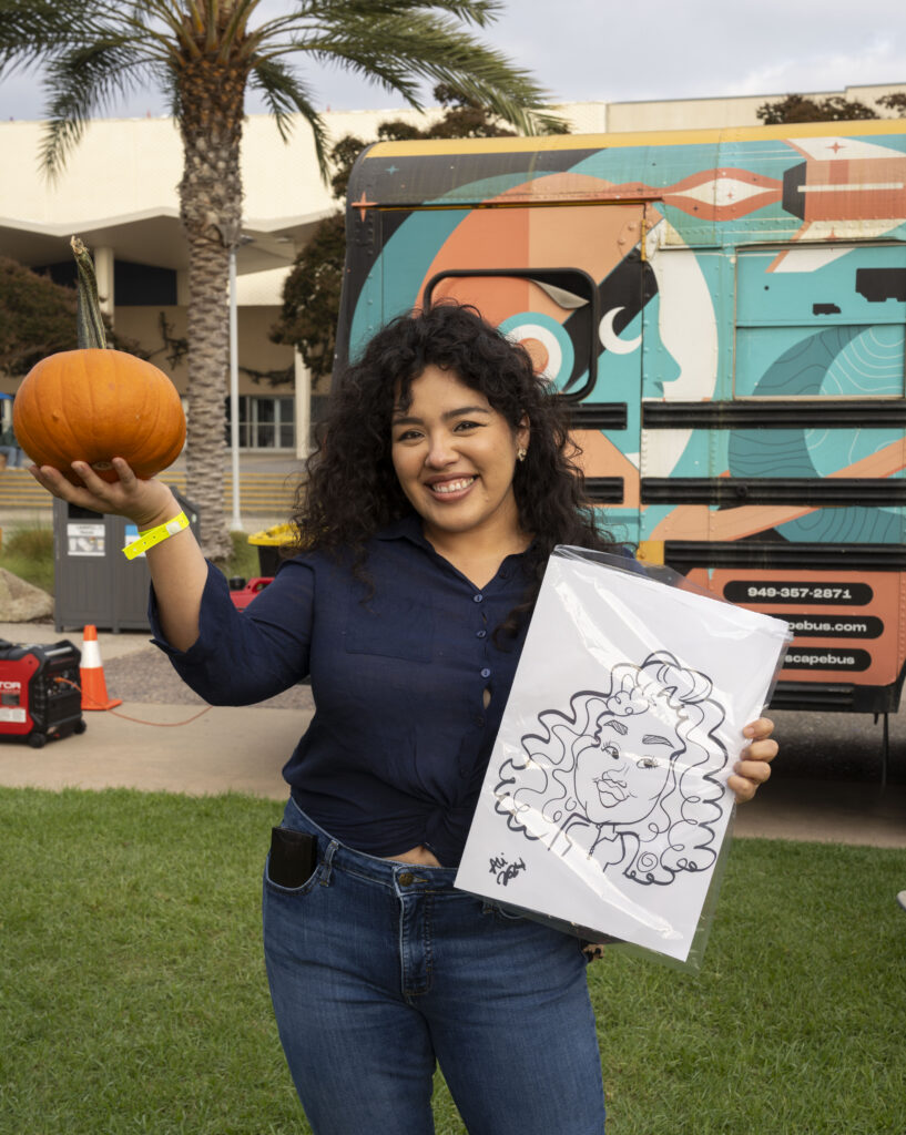 a young woman poses with a pumpkin and a caricature drawing