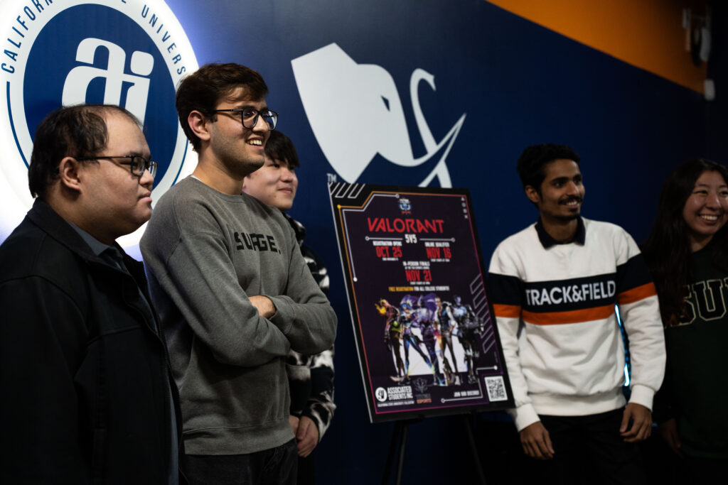a group of guys pose in  front of Valorant signage