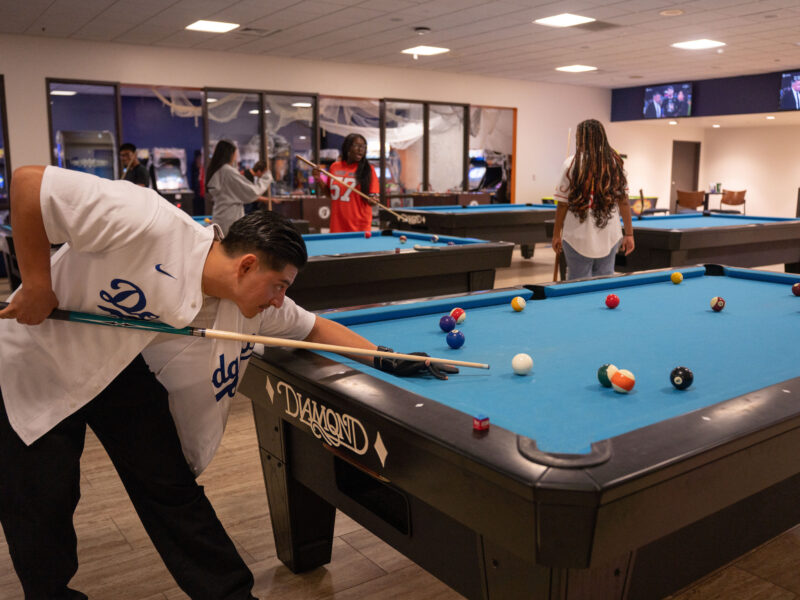 A man bending down to play a game of billiards.