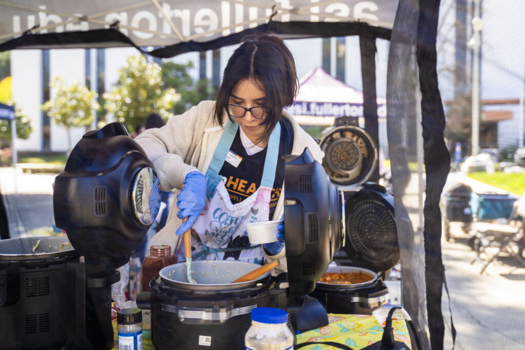 a woman in an apron mixes food in a pot