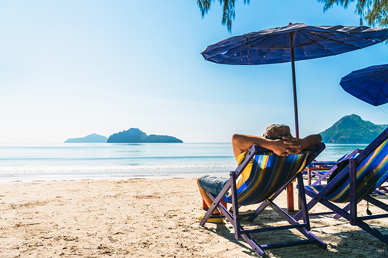 person lounging on the beach under an umbrella