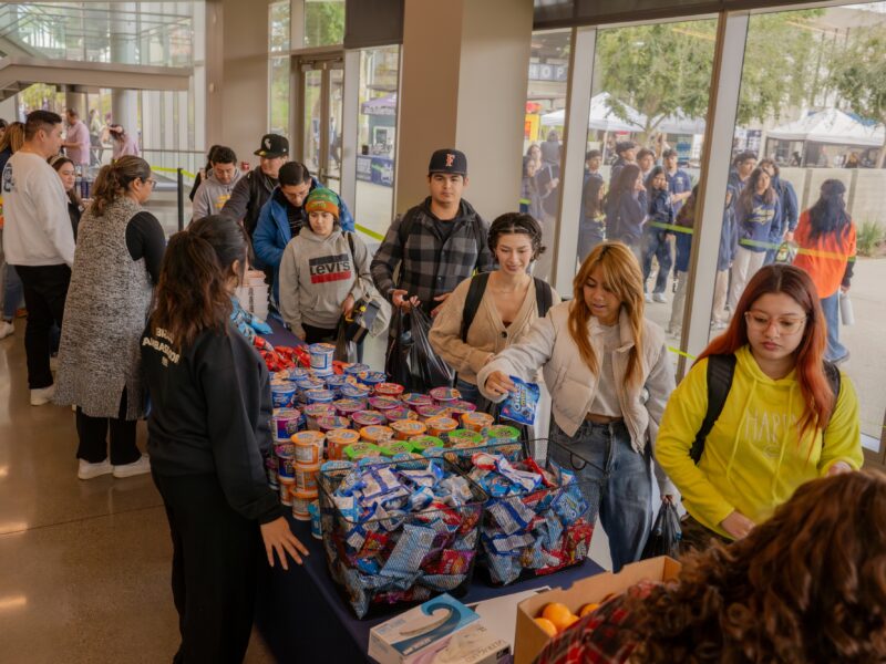 a group of students line up with grocery bags to collect groceries