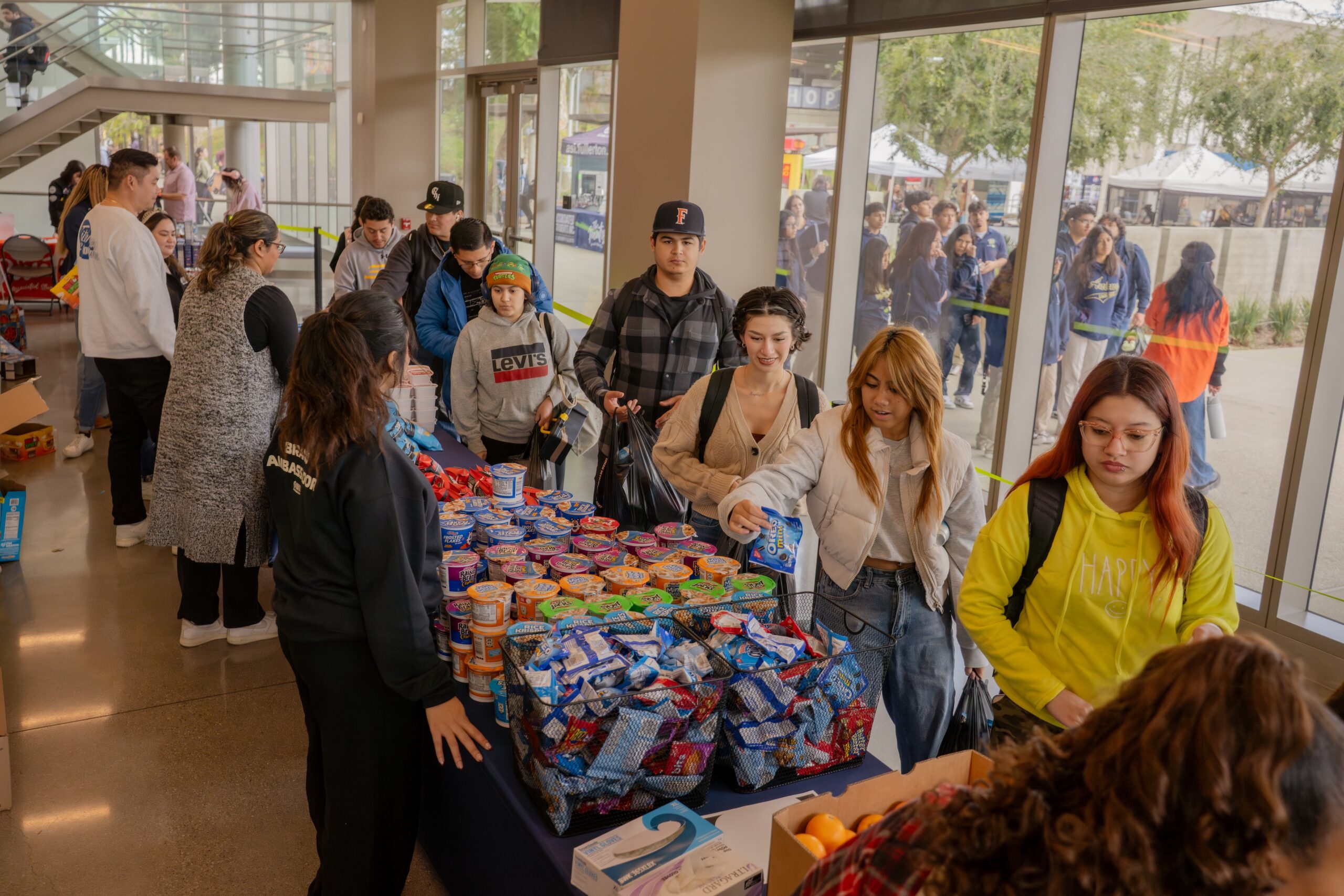 a group of students line up with grocery bags to collect groceries