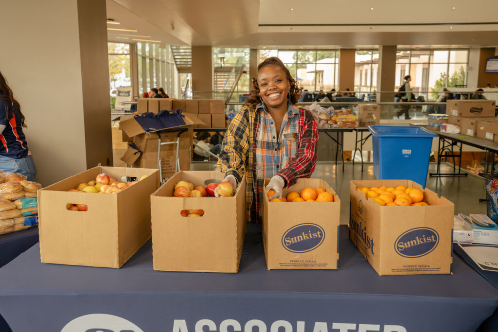 a woman stands behind boxes of oranges
