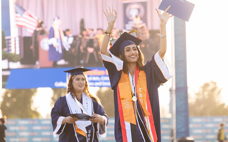 two students walking across stage at commencement