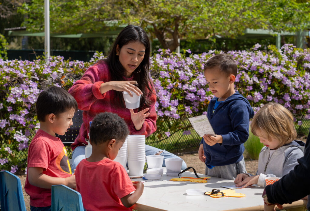 a group of children play with a teacher at a table