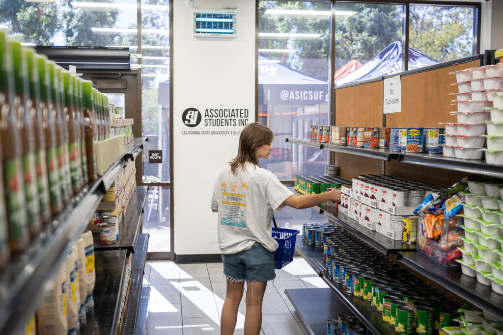 A person picking up a can from a shelf.