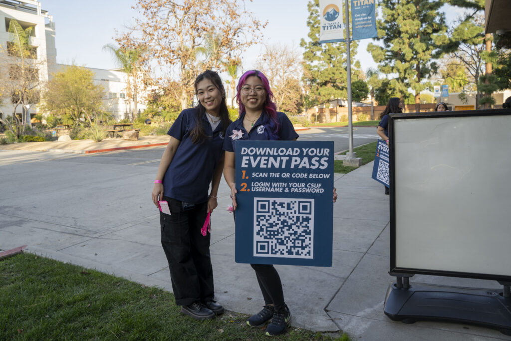 Lam and fellow programming assistant hold event signage outside of event