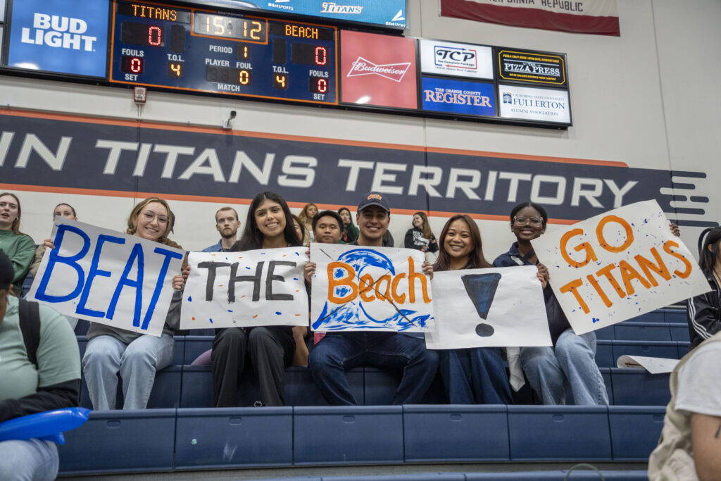 a group of college students holding up signs at a basketball game