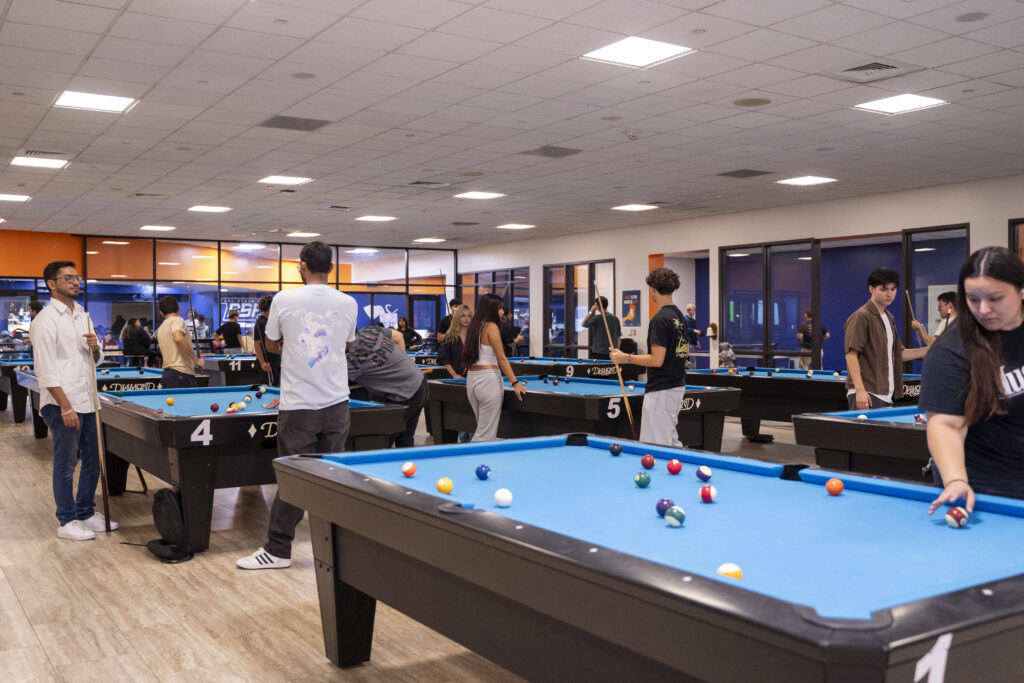 a group of college students playing pool in a billards room