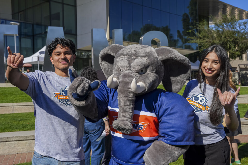 two college students pose with an elephant mascot 