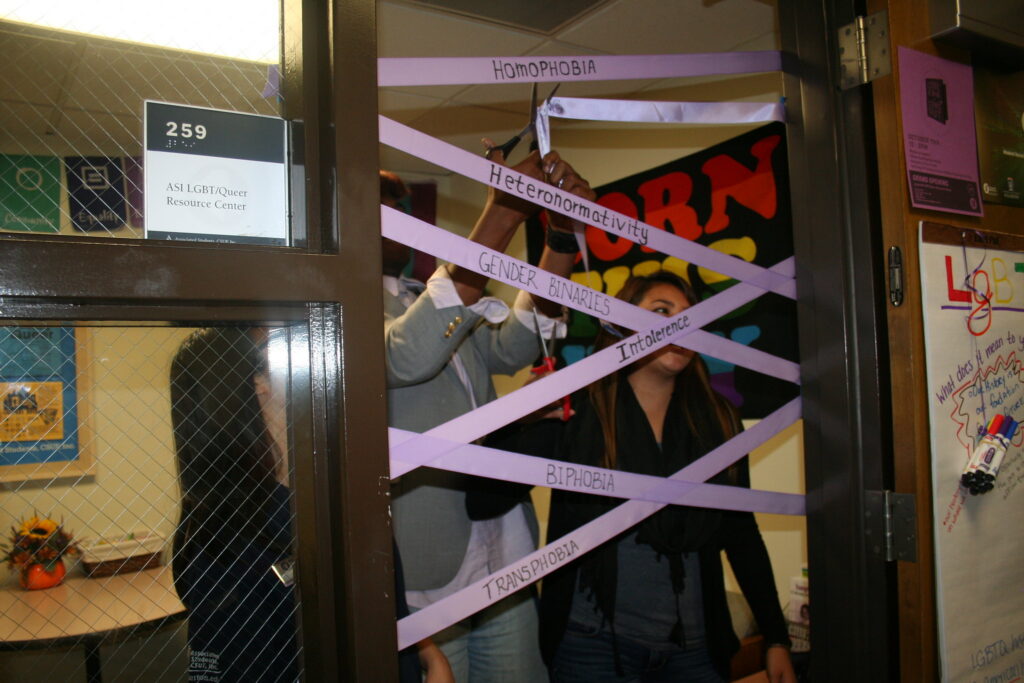 Three people cut through ribbon with a pair of scissors.