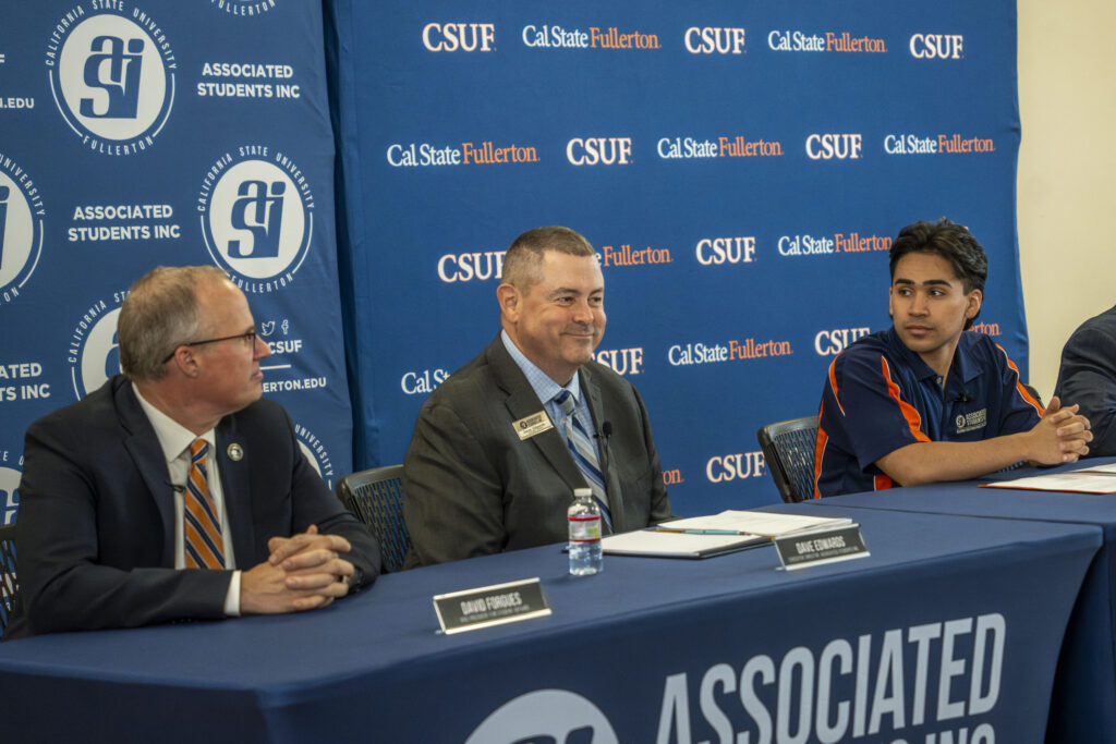 three men wist at a press conference table