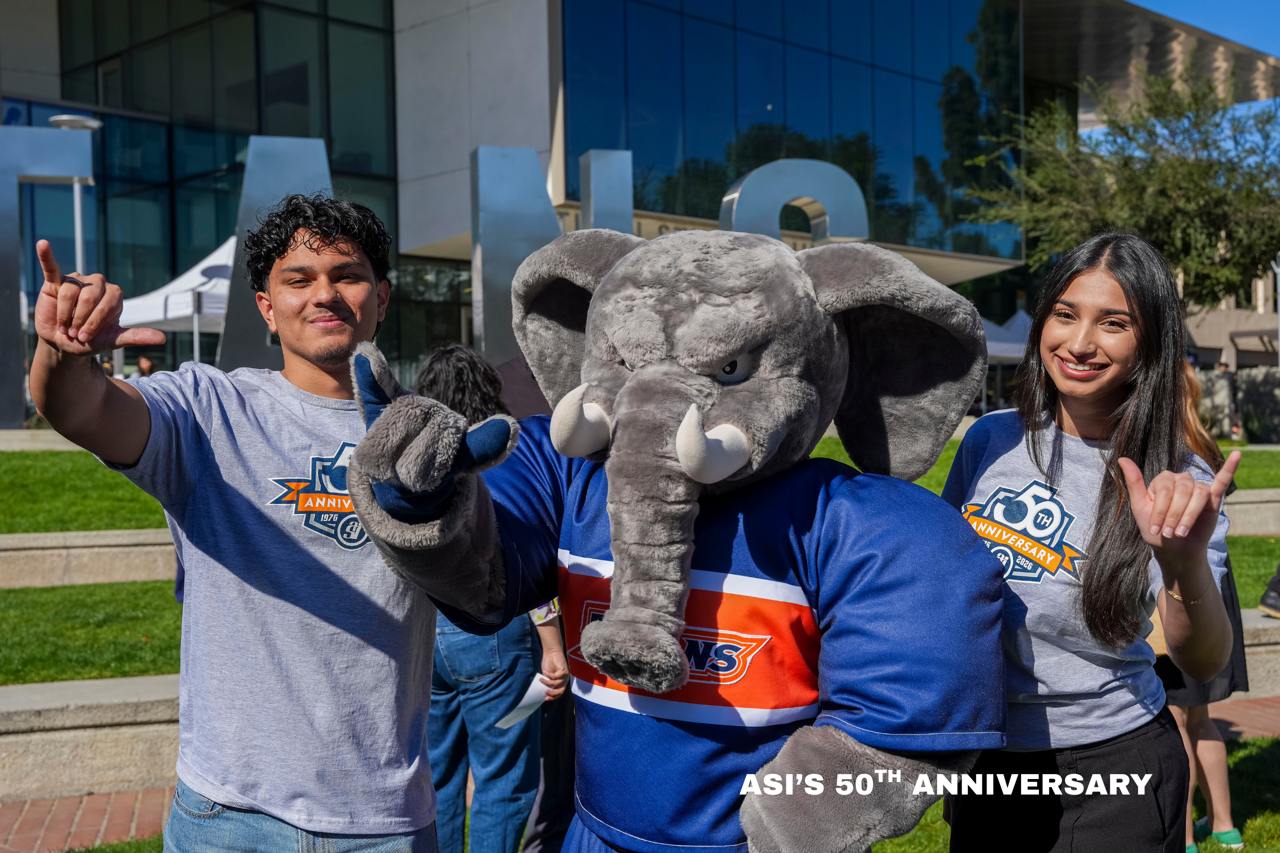 two college students pose with a mascot elephant