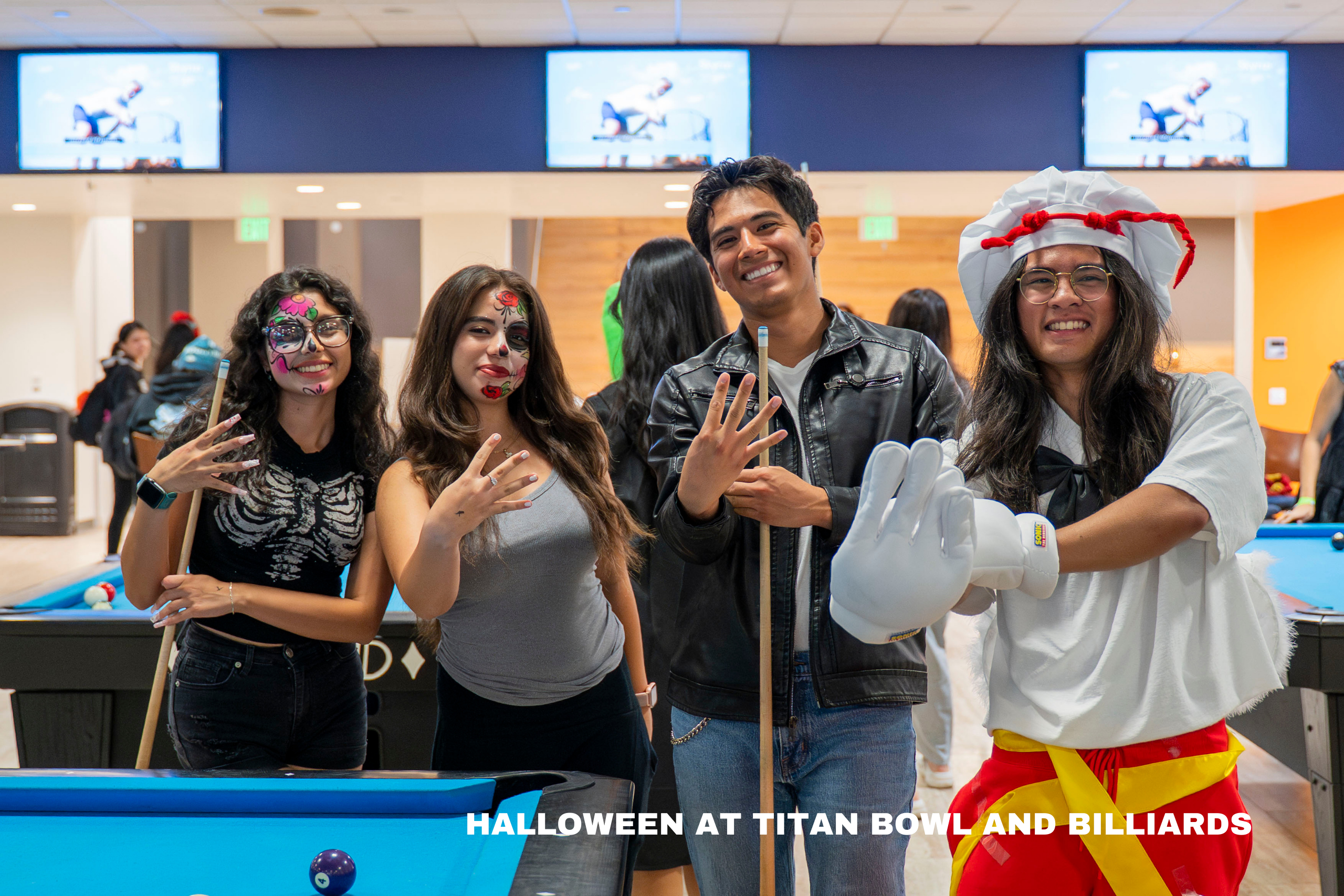 college students pose at a pool table dressed in halloween costumes
