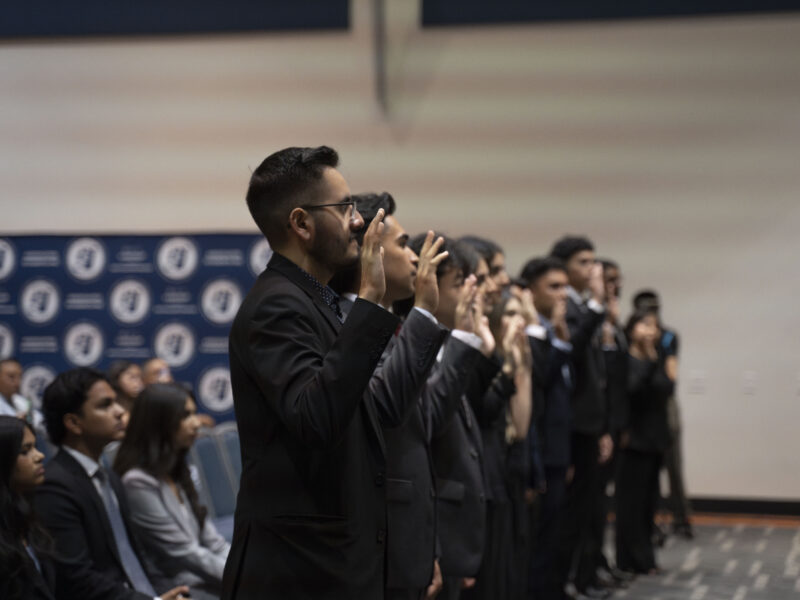 a group of students in suits with their hands raised