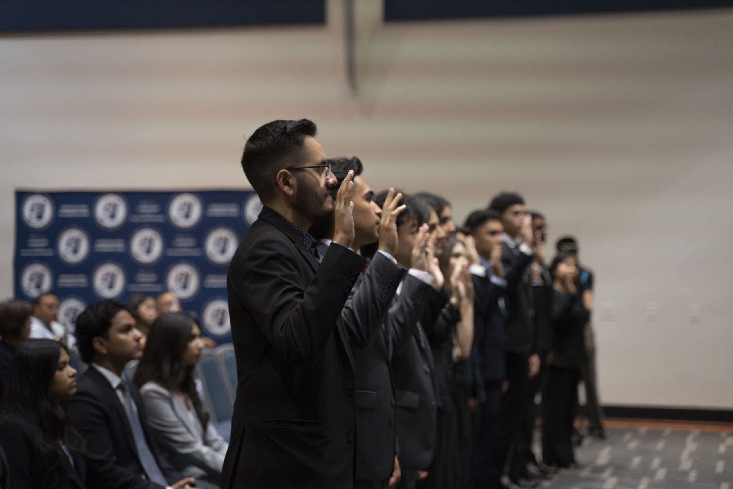 a group of students in suits with their hands raised