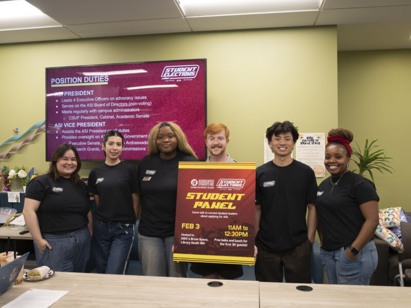 a group of college students stand in a line and pose with a foam board