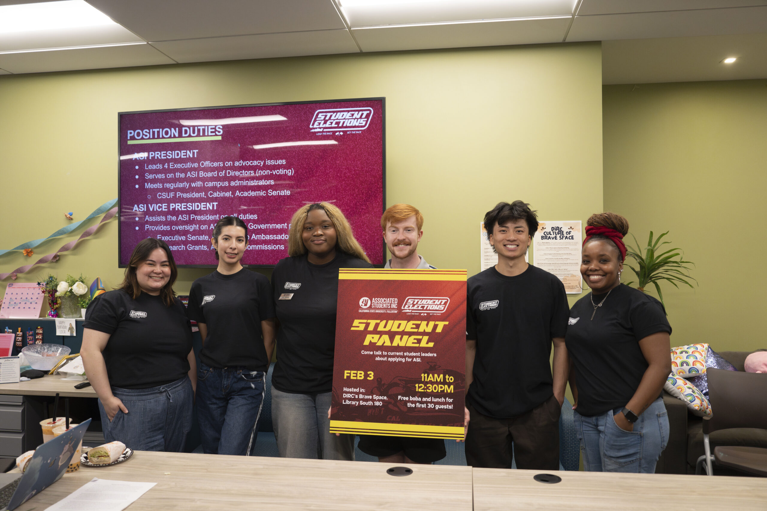 a group of college students stand in a line and pose with a foam board